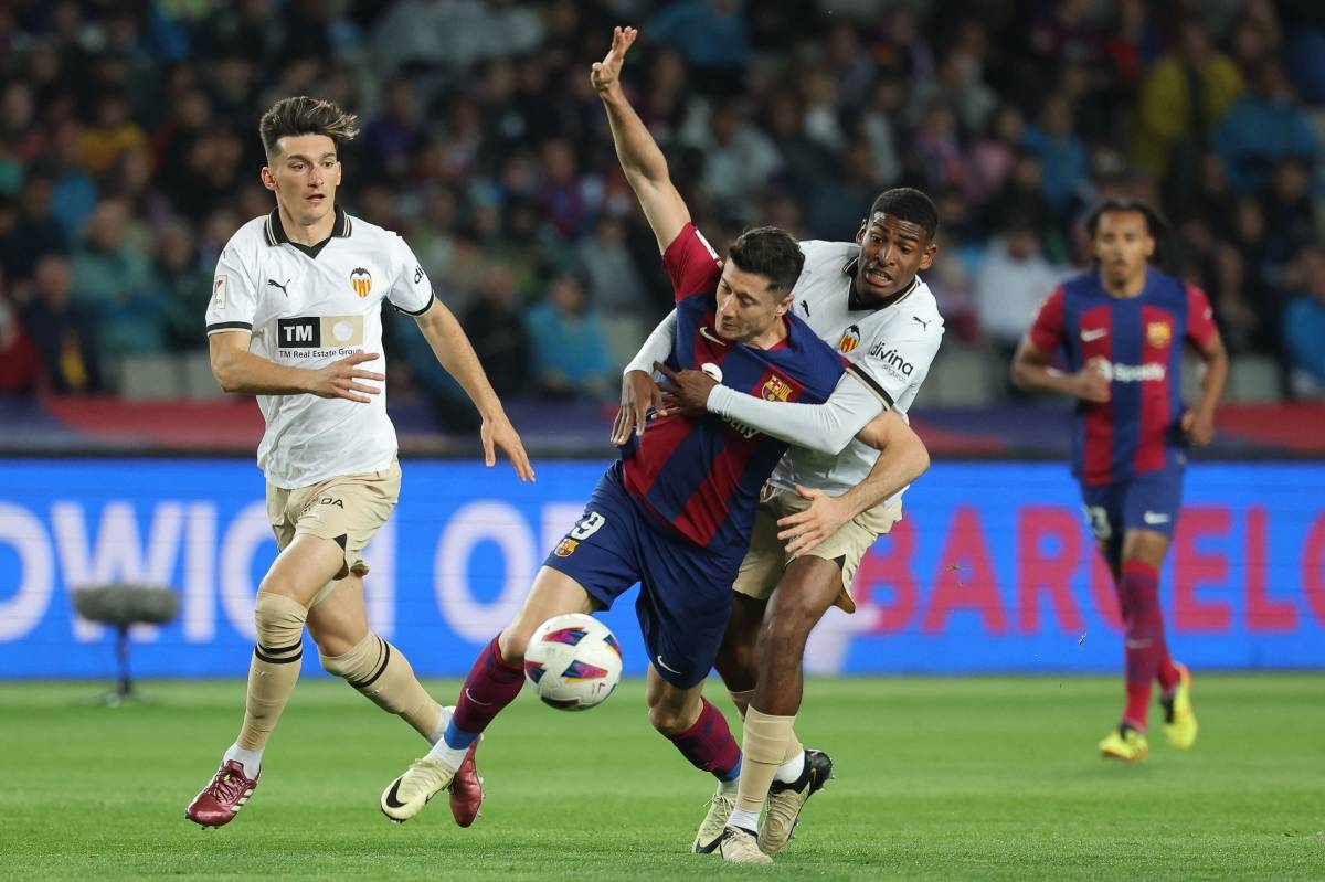 STAY HERE Barcelona’s Polish forward Robert Lewandowski (center) fights for the ball with Valencia’s Spanish defender Cristhian Mosquera during the Spanish league football match between FC Barcelona and Valencia CF at the Estadi Olimpic Lluis Companys in Barcelona on Monday, April 29, 2024. PHOTO BY LLUIS GENE/AFP