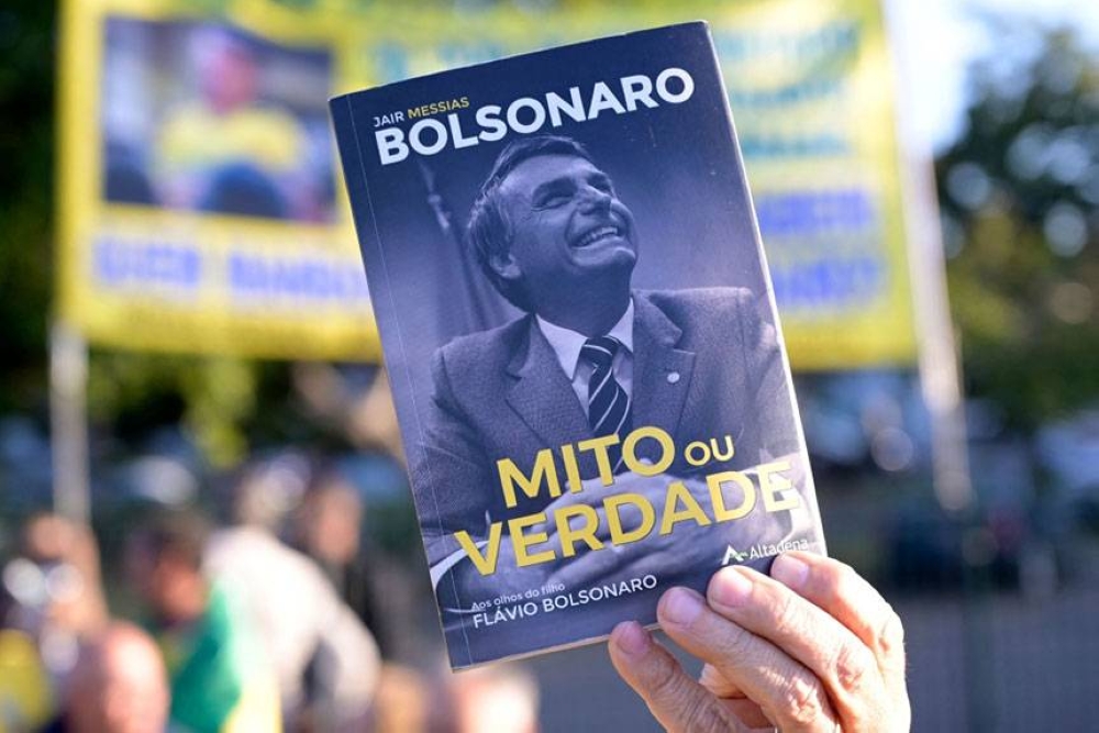 ELECTION HEAT A supporter of Brazil’s President Jair Bolsonaro holds the book Myths or Truth, written by his son Flavio Bolsonario, during a gathering at Pampulha Airport in Belo Horizonte, Minas Gerais, Brazil on Thursday, May 26, 2022 (May 27 in Manila), after he participated in the delivery of affordable housing in Coronel Fabriciano and in the inauguration of the re-elected board of the Minas Gerais State Federation of Industries in Belo Horizonte. AFP PHOTO