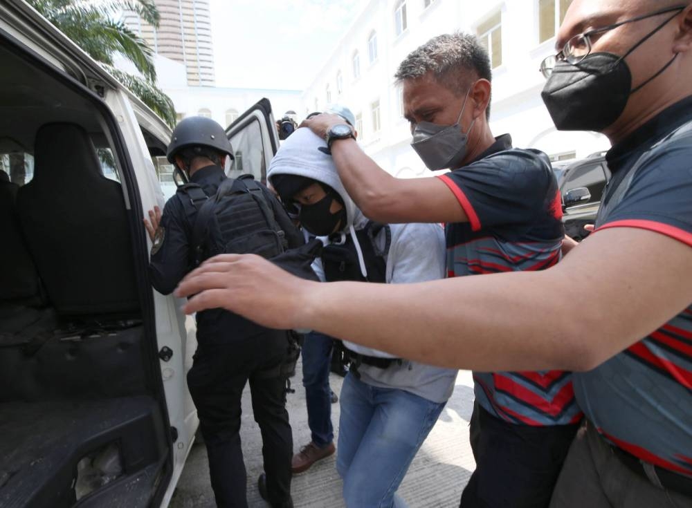 Policemen escort Joel Salve Escorial, who shot and killed broadcaster Percy Lapid, during the preliminary hearing of the murder case filed against him at the Department of Justice on Monday, October 24, 2022. PHOTO BY RENE H. DILAN