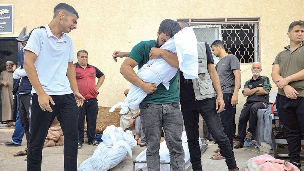 FATHER’S GRIEF A man reacts as he carries the shrouded body of his child in front of the morgue of the Al-Aqsa hospital in Deir Balah in the central Gaza Strip, following an Israeli strike on Sunday, Oct. 22, 2023, as battles continue between Israel and the Palestinian Hamas group. AFP PHOTO