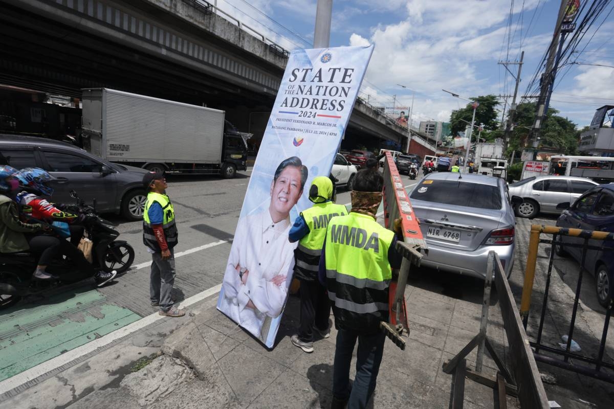 Metropolitan Manila Development Authority workers install tarpaulins along a portion of EDSA in Quezon City on July 19, 2024 ahead of President Ferdinand Marcos Jr.'s State of the Nation Address. PHOTO BY JOHN ORVEN VERDOTE