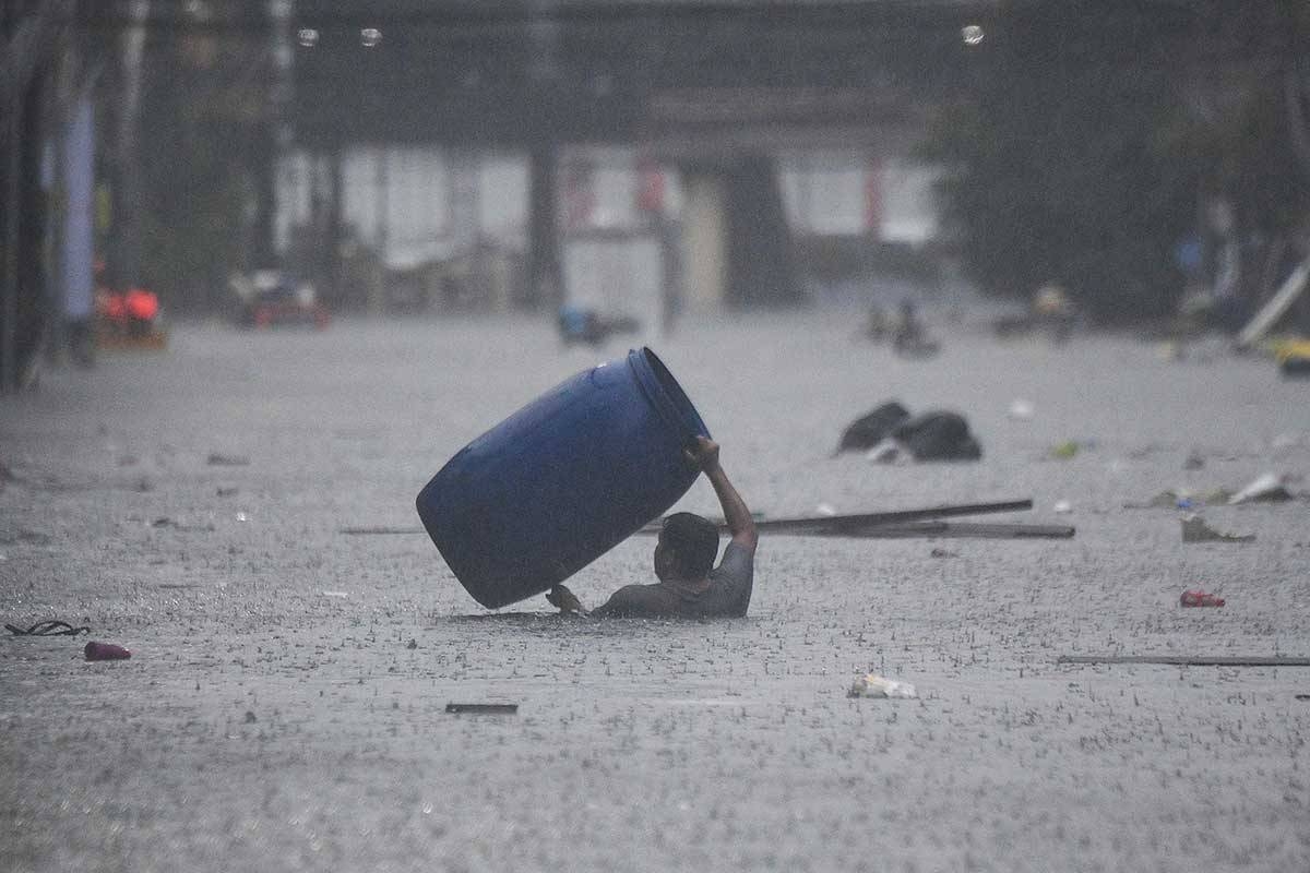 WATERY WORLD A man carrying a plastic container wades through a flooded street in Manila on July 24, 2024 amid heavy rains. AFP PHOTO