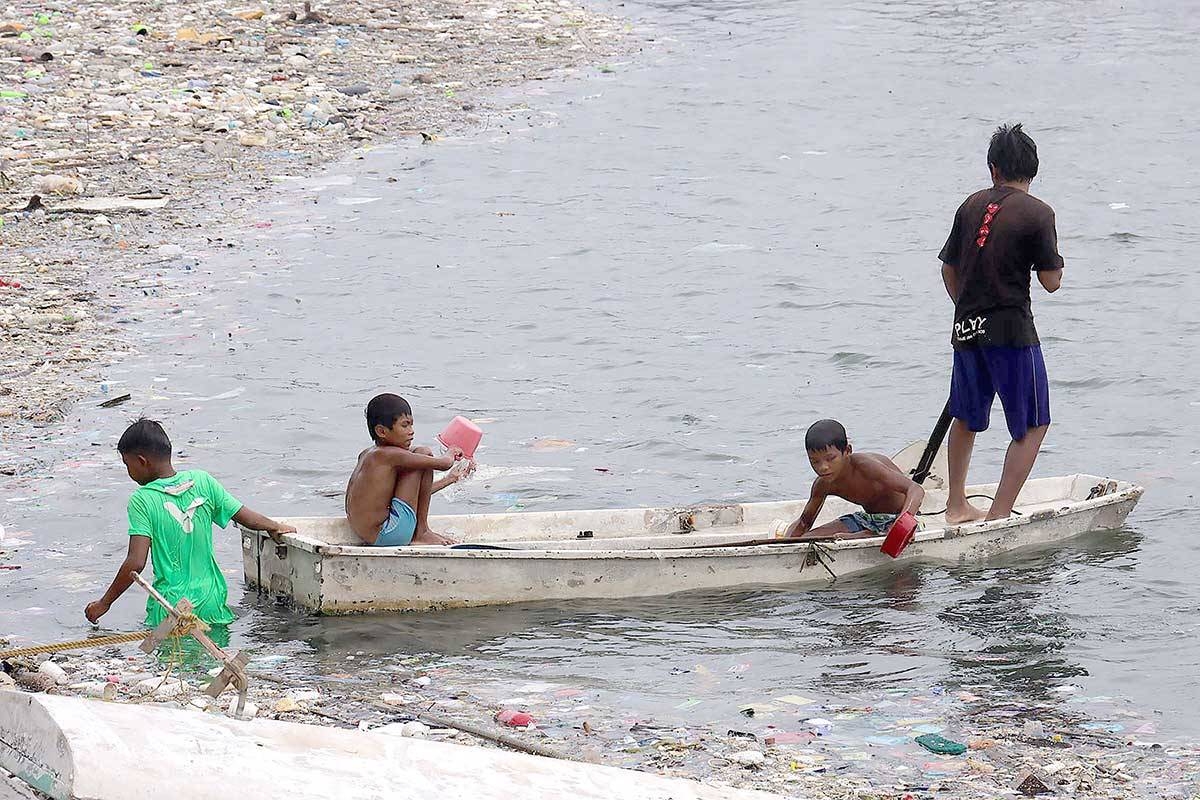 SCAVENGERS Children collect trash in Manila Bay on July 25, 2024, a day after floods swamped the city and other areas in Metro Manila. PHOTO BY J. GERARD SEGUIA