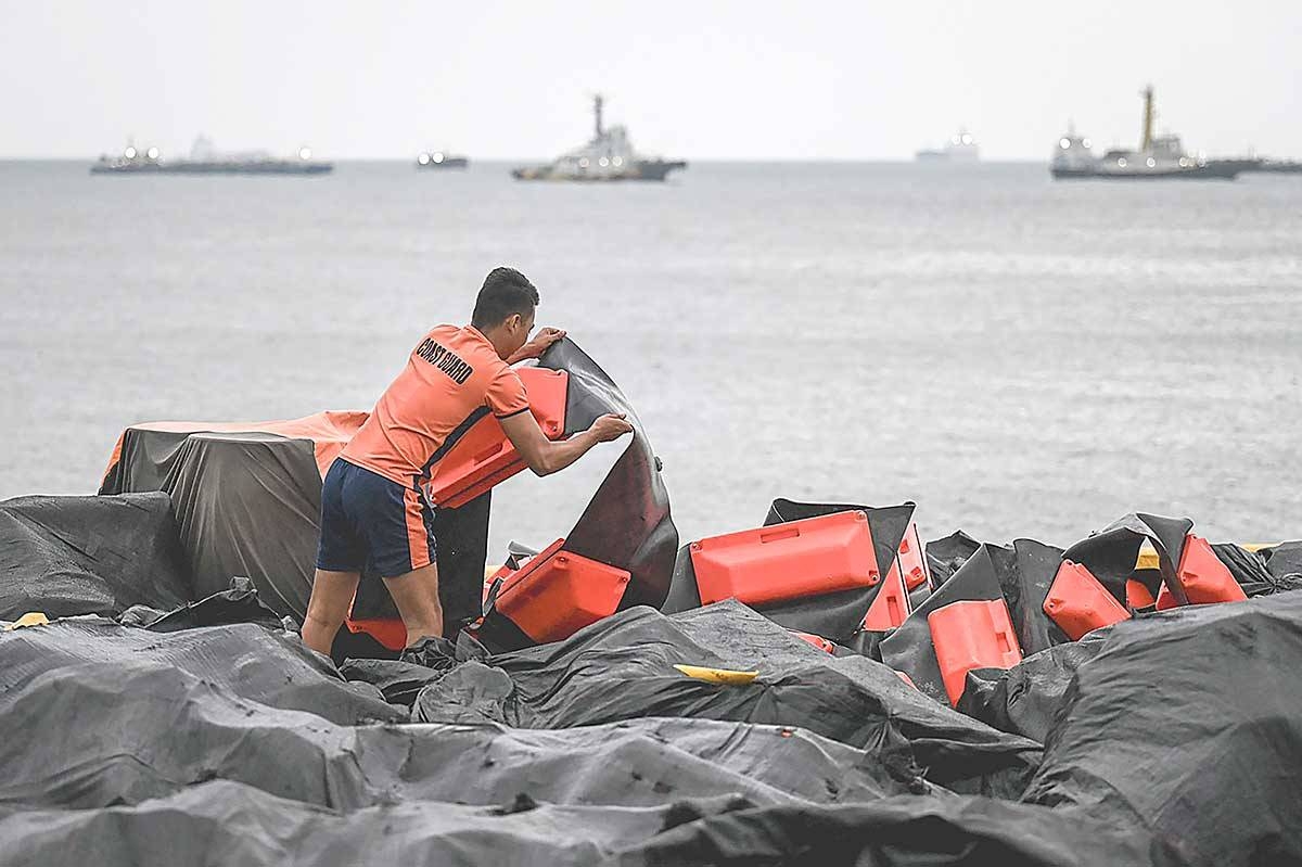 STOPPING THE SPILL Coast guard personnel arrange an oil spill containment boom to be on standby for deployment at a port in Limay, Bataan, on July 25, 2024. A Philippine-flagged tanker carrying 1.4 million liters of industrial fuel oil sank off Manila on July 25, authorities said, as they raced to contain a spill. PHOTO BY AFP