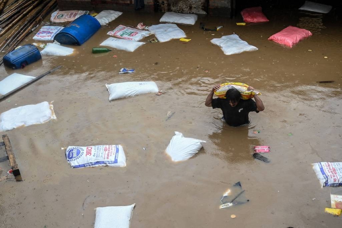 SALVAGING SACKS A man carrying a sack of flour from his shop wades through floodwaters after the Bagmati river overflowed during monsoon rains in Nepal’s capital Kathmandu on Sept. 28, 2024. AFP PHOTO