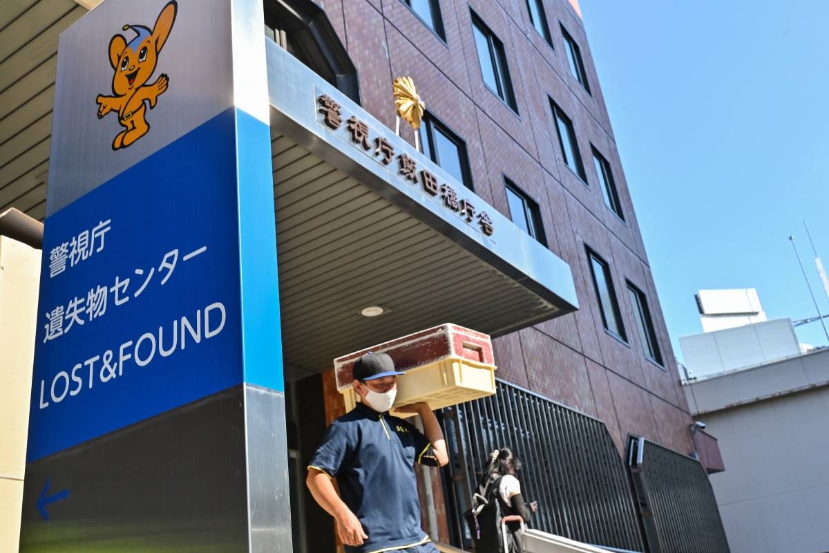 This photo taken on August 2, 2024 shows a delivery man leaving the Tokyo Metropolitan Police Department Lost and Found Centre in the Iidabashi area of central Tokyo. - Soft toys, forlorn suitcases and a forest of umbrellas: welcome to Tokyo's vast police lost-and-found centre, where everything is meticulously tagged and sorted to hasten a return to its rightful owner. (Photo by Richard A. Brooks / AFP) / TO GO WITH: TOKYO-LIFESTYLE-TRANSPORT, REPORTAGE BY NATSUKO FUKUE