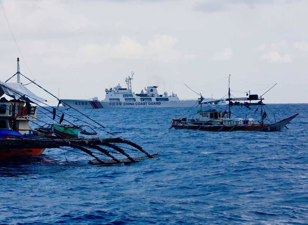 In this file photo shows a Chinese Coast Guard (CCG) patrol ship maneuvers near Filipino fishermen aboard motorized wooden boats sailing towards Scarborough Shoal in the disputed South China Sea, 16 May 2024. EPA-EFE/FRANCIS R. MALASIG