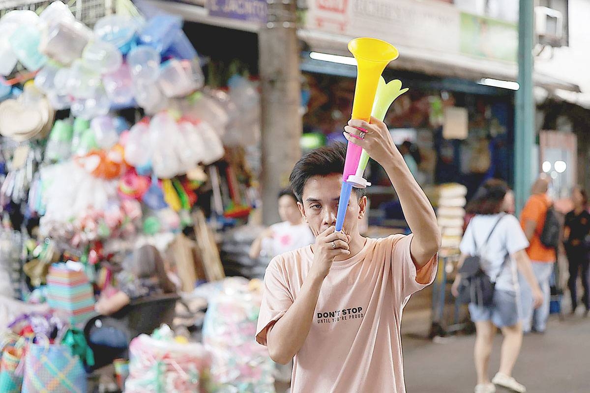 NOISE MAKER A man checks out a horn he bought at a market in Marikina City on Dec. 28, 2024, as the nation prepares to welcome the new year. PHOTO BY JOHN ORVEN VERDOTE