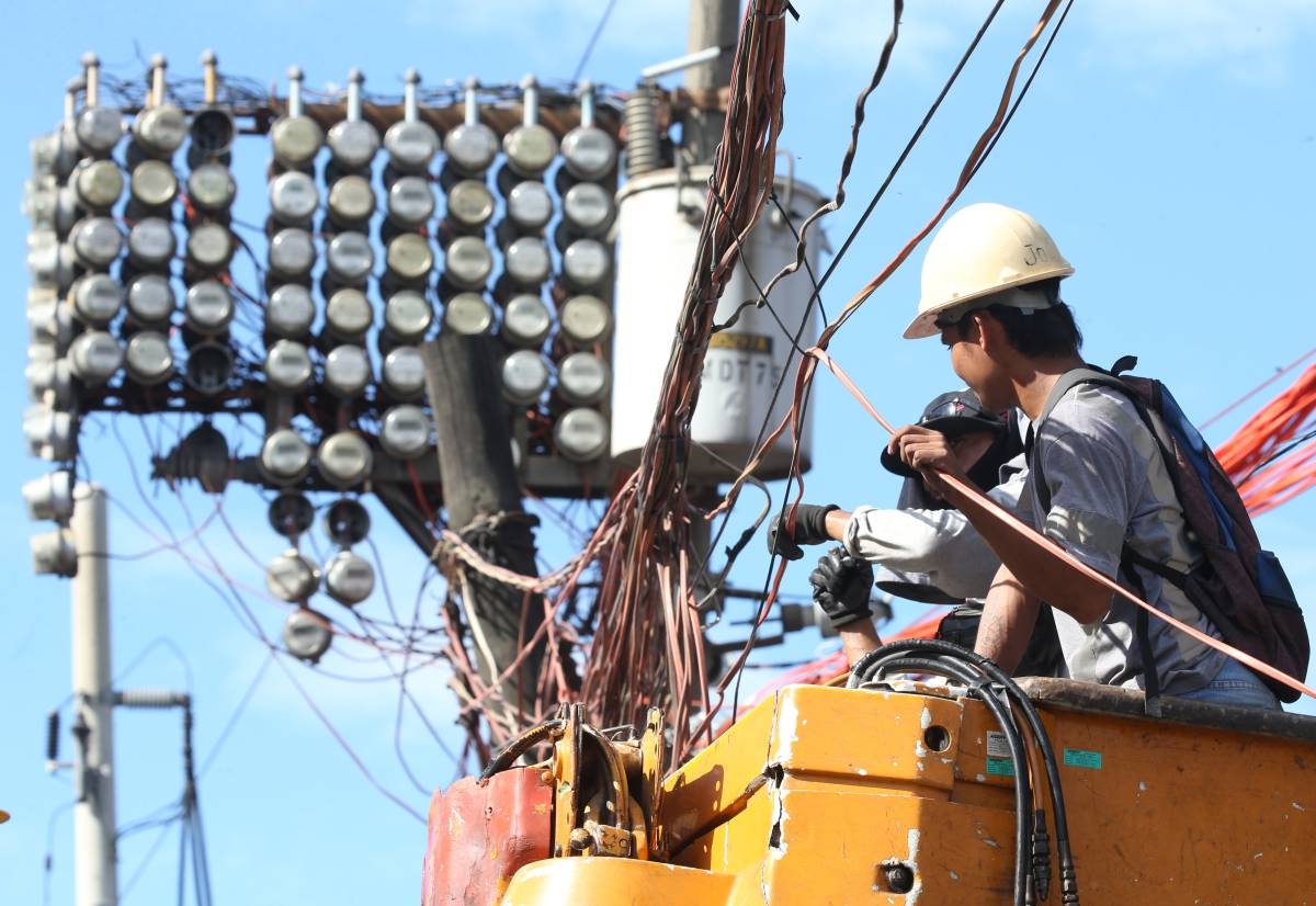 Power company workers fix electric wires in Navotas City on Jan. 16, 2025. Power distribution giant Manila Electric Co. (Meralco) indicated lower electricity rates this January due to a decrease in generation costs. PHOTOS BY RENE H. DILAN