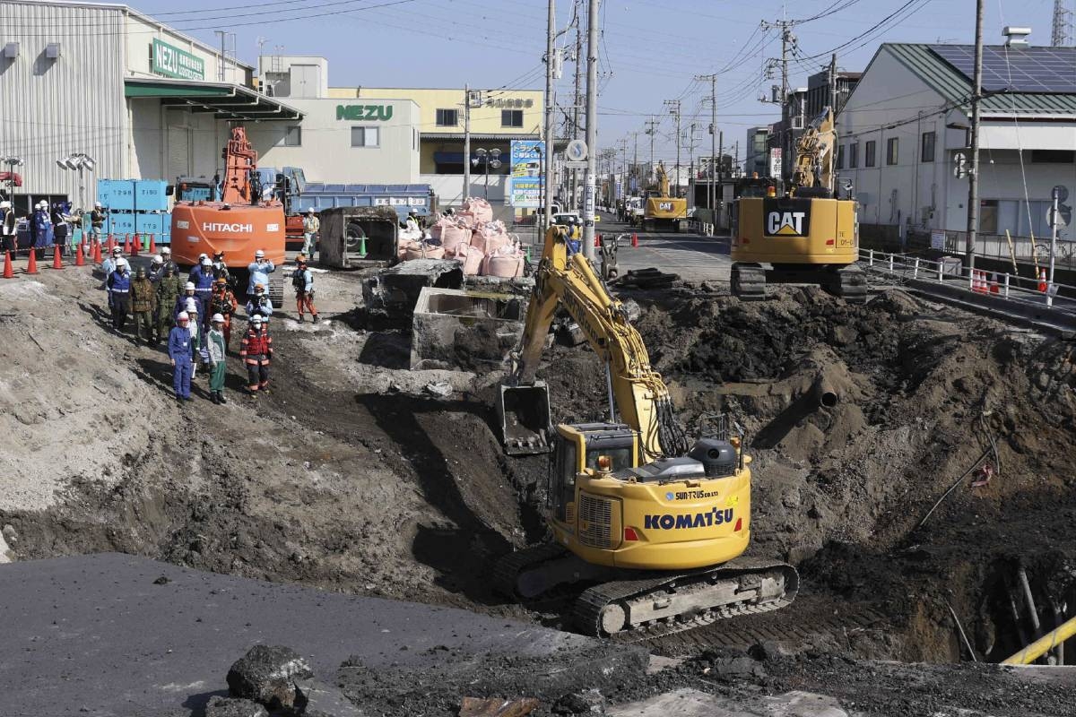 Excavators and rescue personnel working to construct a slope for rescue operations are seen at the site where a truck on January 28 plunged into a sinkhole, trapping the vehicle's driver, in Yashio, Saitama Prefecture on February 1, 2025. Japanese rescuers completed building a slope on February 1 to reach a truck driver stuck in a sinkhole, officials said, four days after his vehicle was swallowed by the cavity now 40 metres wide. (Photo by JIJI PRESS / AFP) / Japan OUT / JAPAN OUT / JAPAN OUT