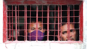 NO WAY OUT Workers of the gutted Kentex Manufacturing peer from the window of the guard house as members of labor groups hold a sympathy protest in front of the gates of the footwear factory, three days after the factory was gutted by a fire killing 72 of its workers, in Valenzuela City in suburban Manila on Friday, May 15. AFP Photo